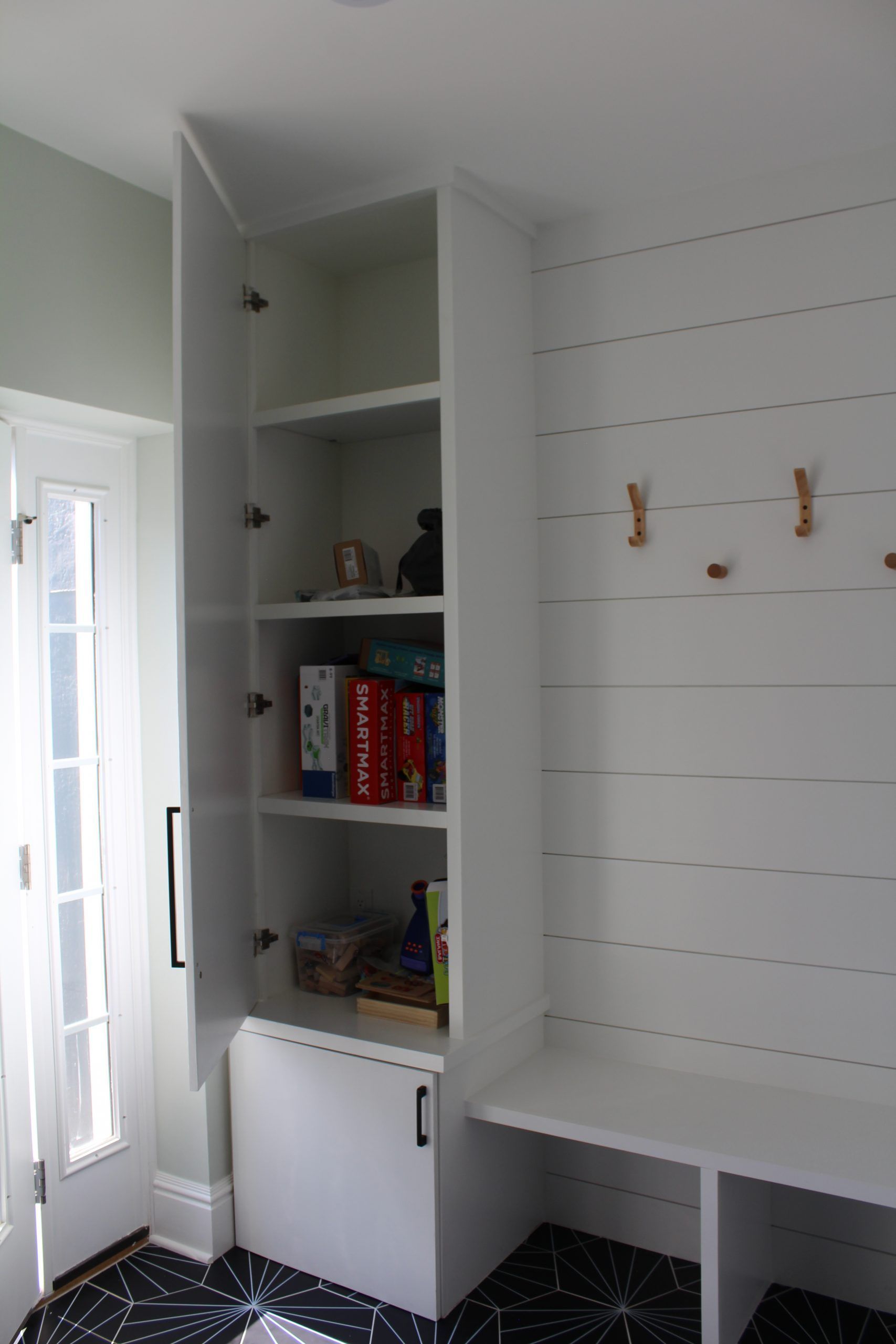 A white shelf with books on it is in a room next to a door.