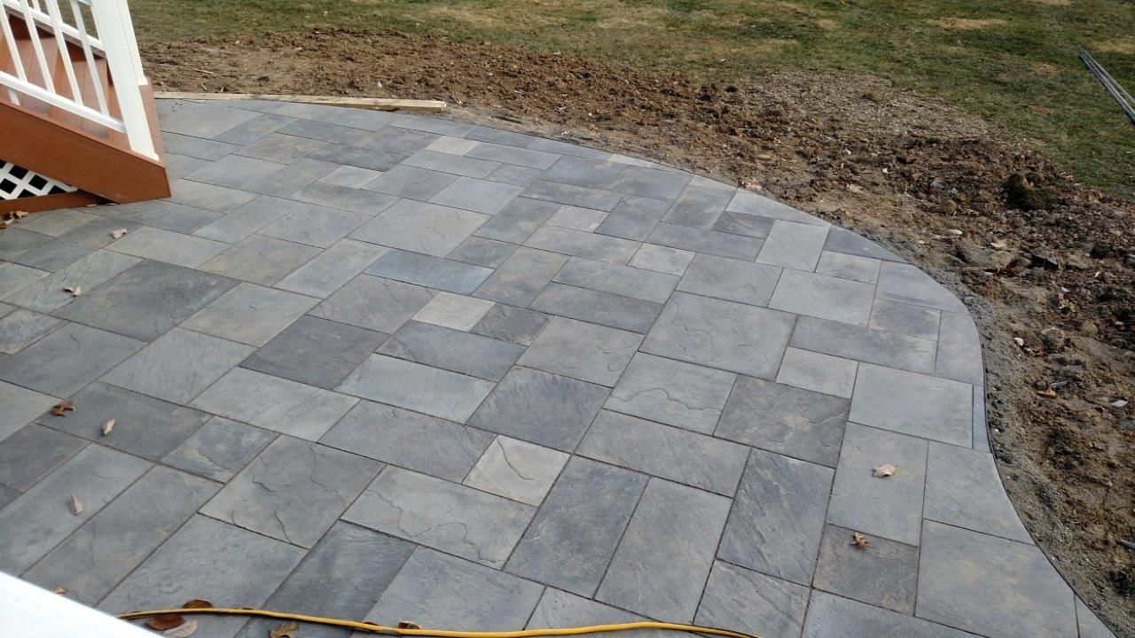 A person is measuring a patio with a tape measure.