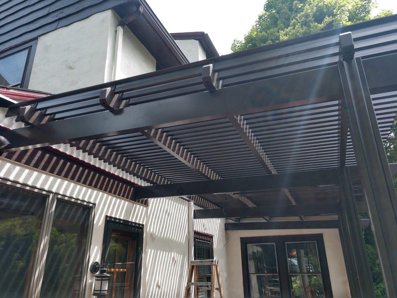 A house with a pergola and a ladder in front of it