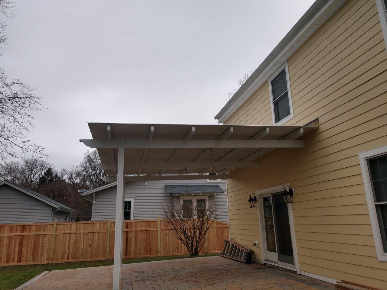 The backyard of a house with a pergola and a wooden fence