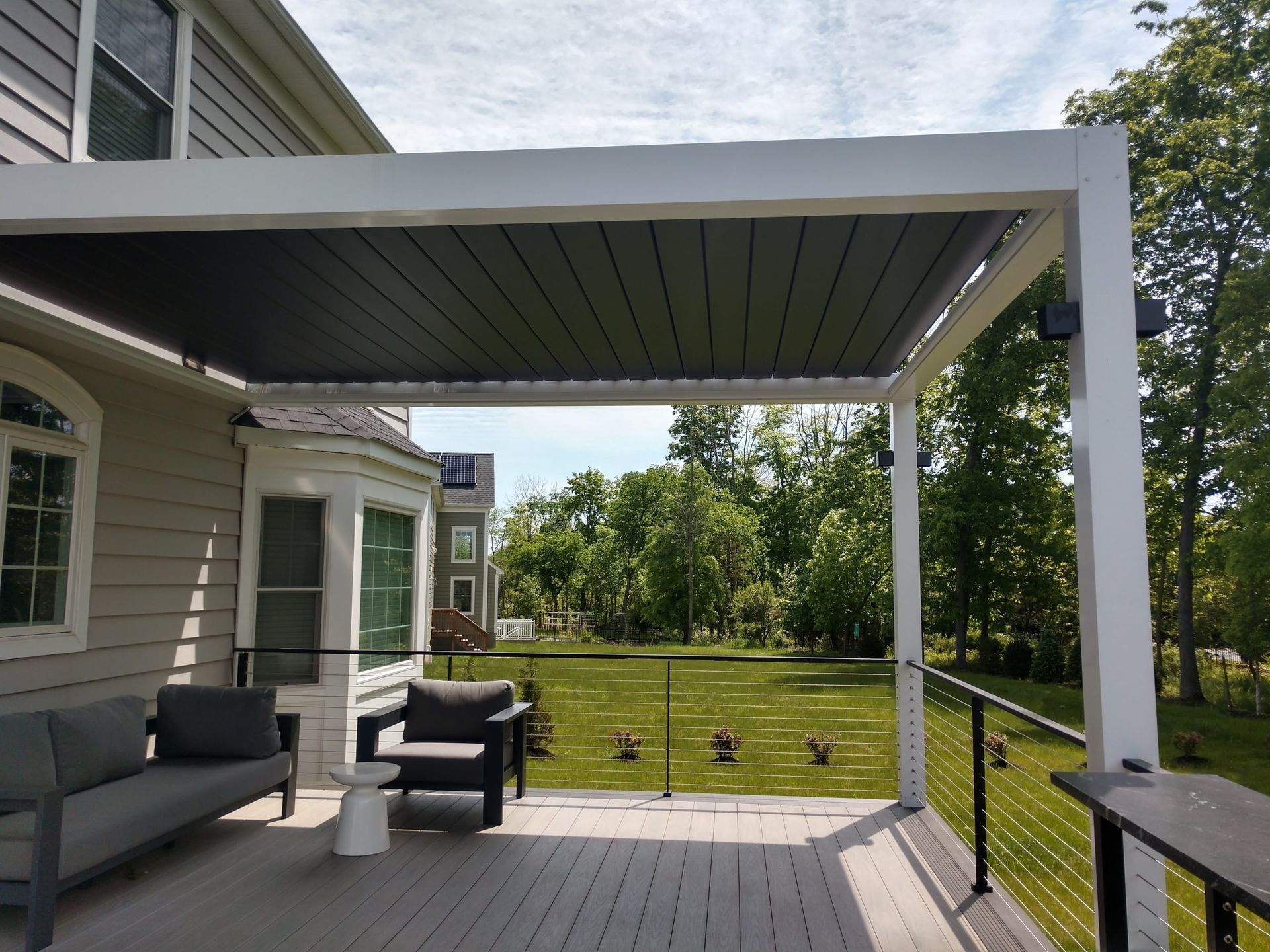 A deck with a couch and chairs under a pergola