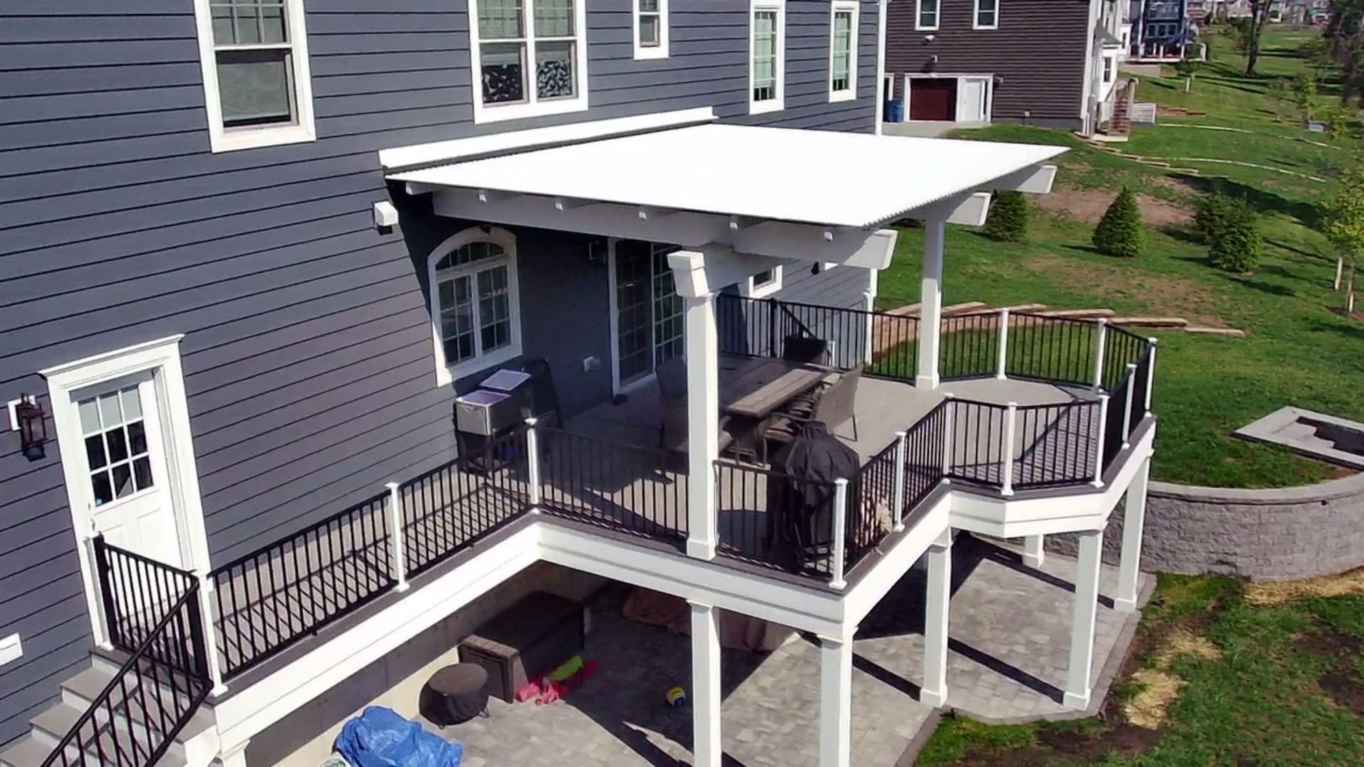 Covered second-story deck with black railings, outdoor dining set, and patio underneath.