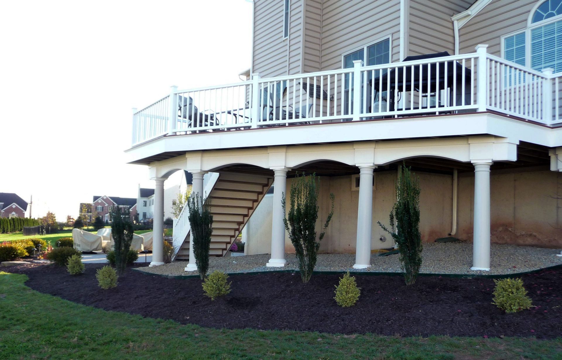 Raised deck with white columns and stairs built by New Dimensions Deck Contractors in NJ