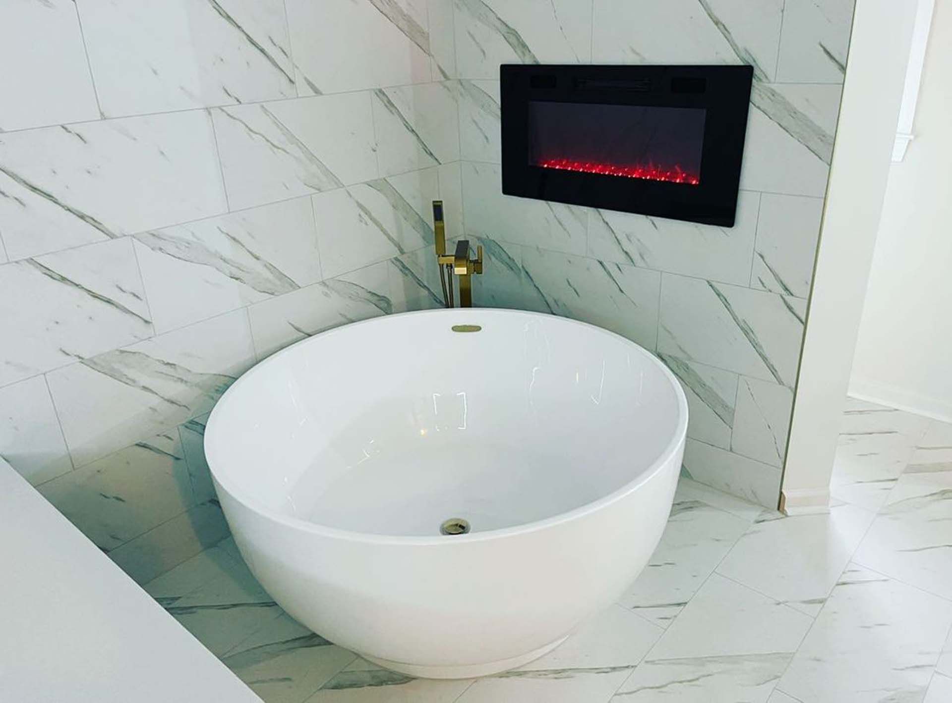 A white bathtub in a bathroom next to a fireplace.