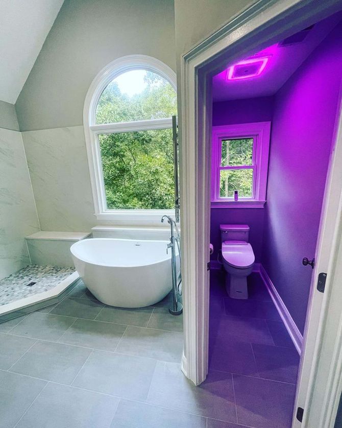 A bathroom with a bathtub , toilet , shower and window.