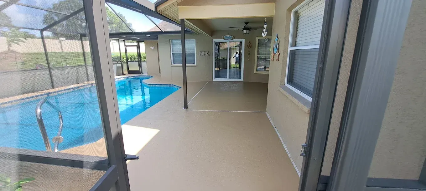 Poolside view of a house with a pool, patio, and glass sliding door.