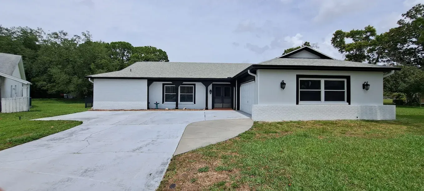White house with black trim and a concrete driveway.