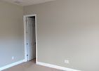 Empty room with light beige walls and a white-trimmed door.