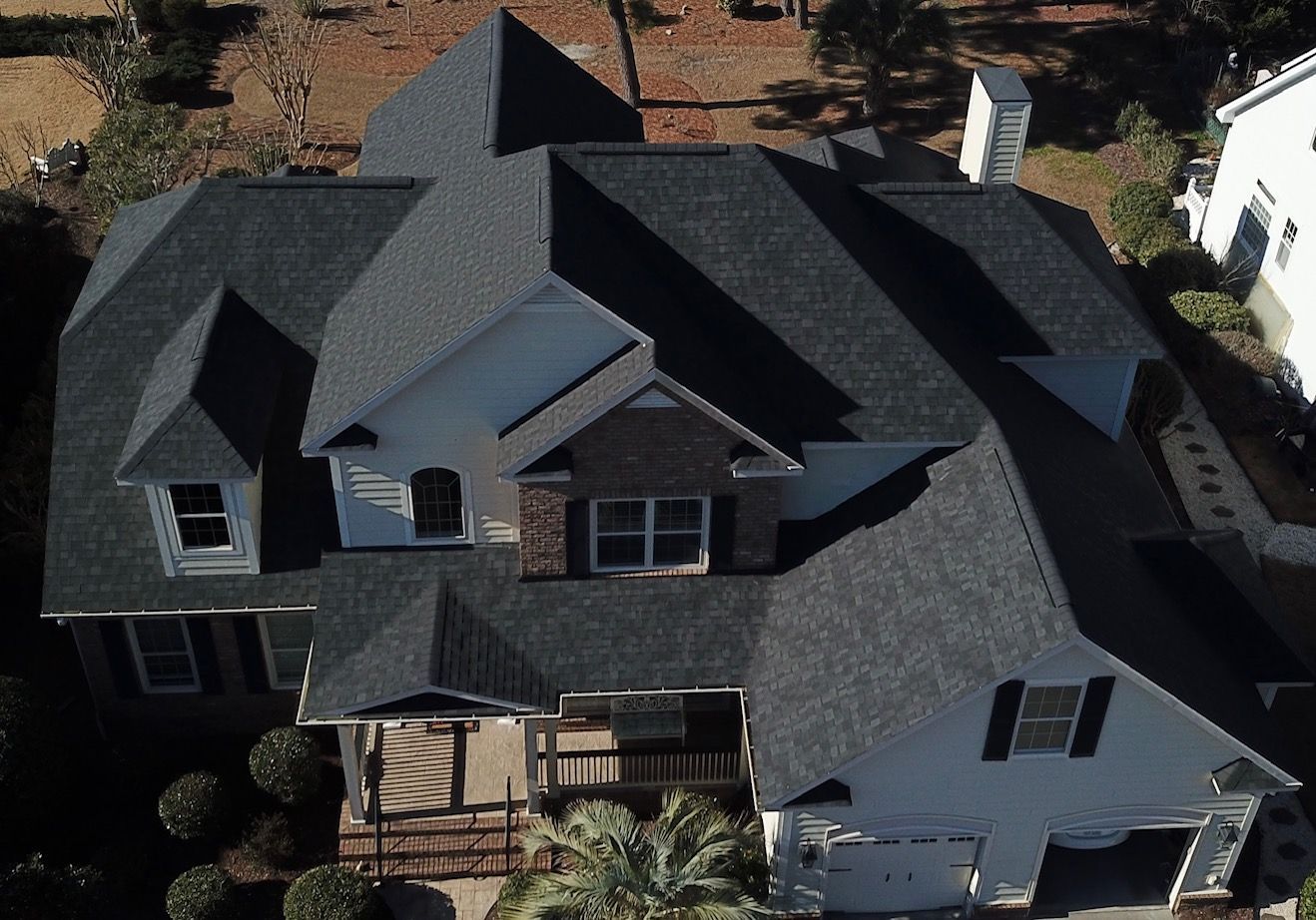 An aerial view of a large house with a black roof