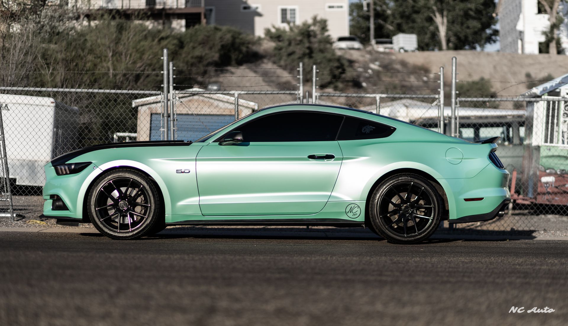 Mint green Ford Mustang with black accents parked outdoors.