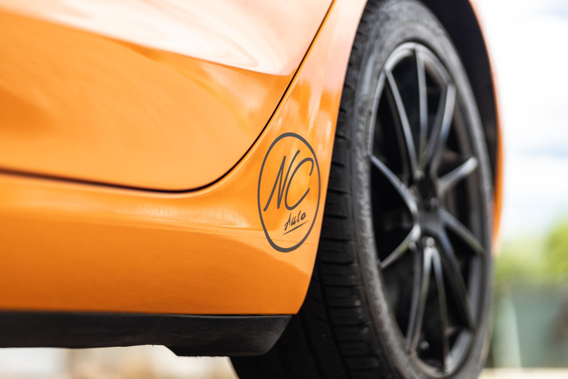 Orange car side panel with black wheel and logo that reads 