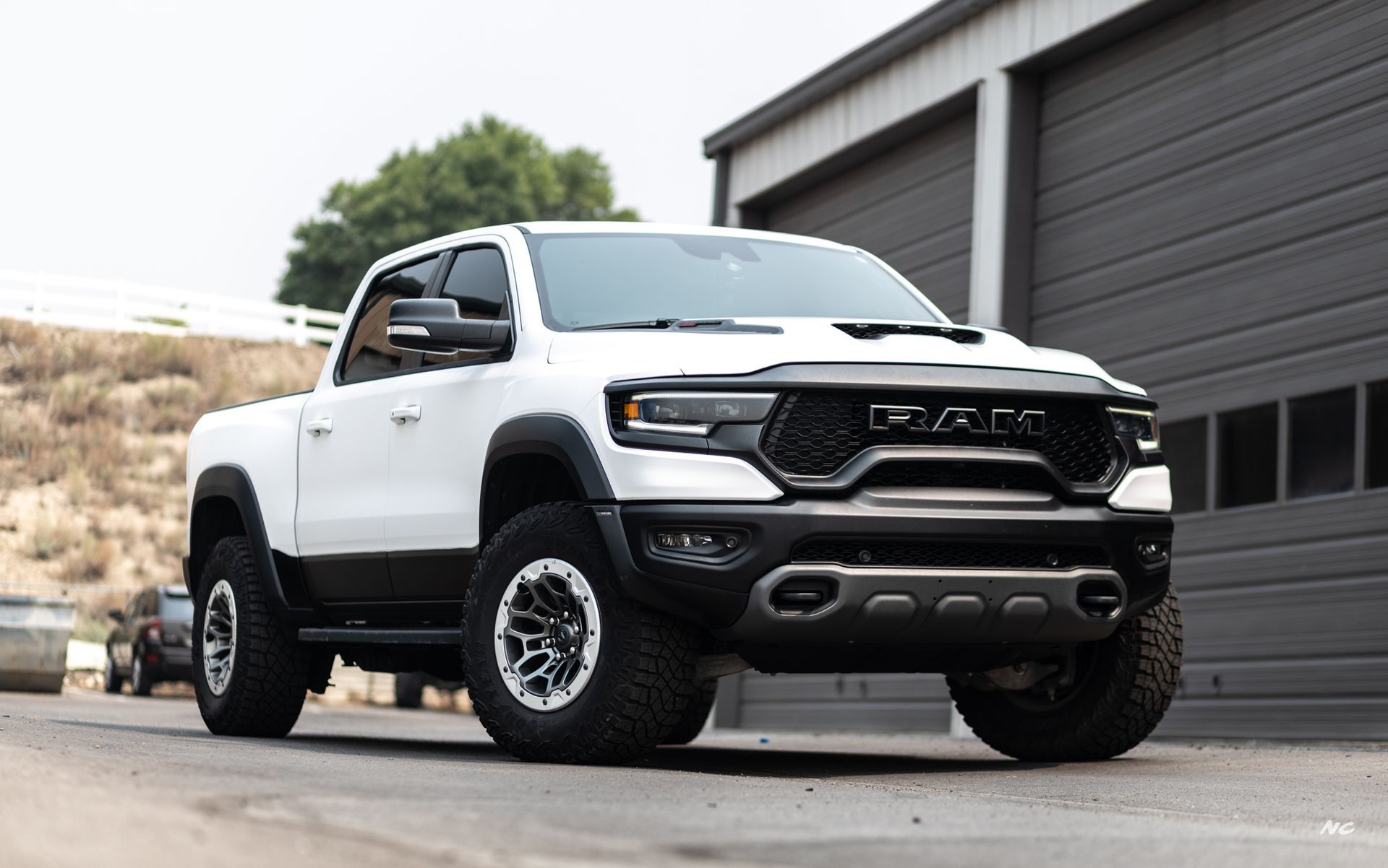 White Ram TRX truck parked in front of a building with a black grill and wheels.