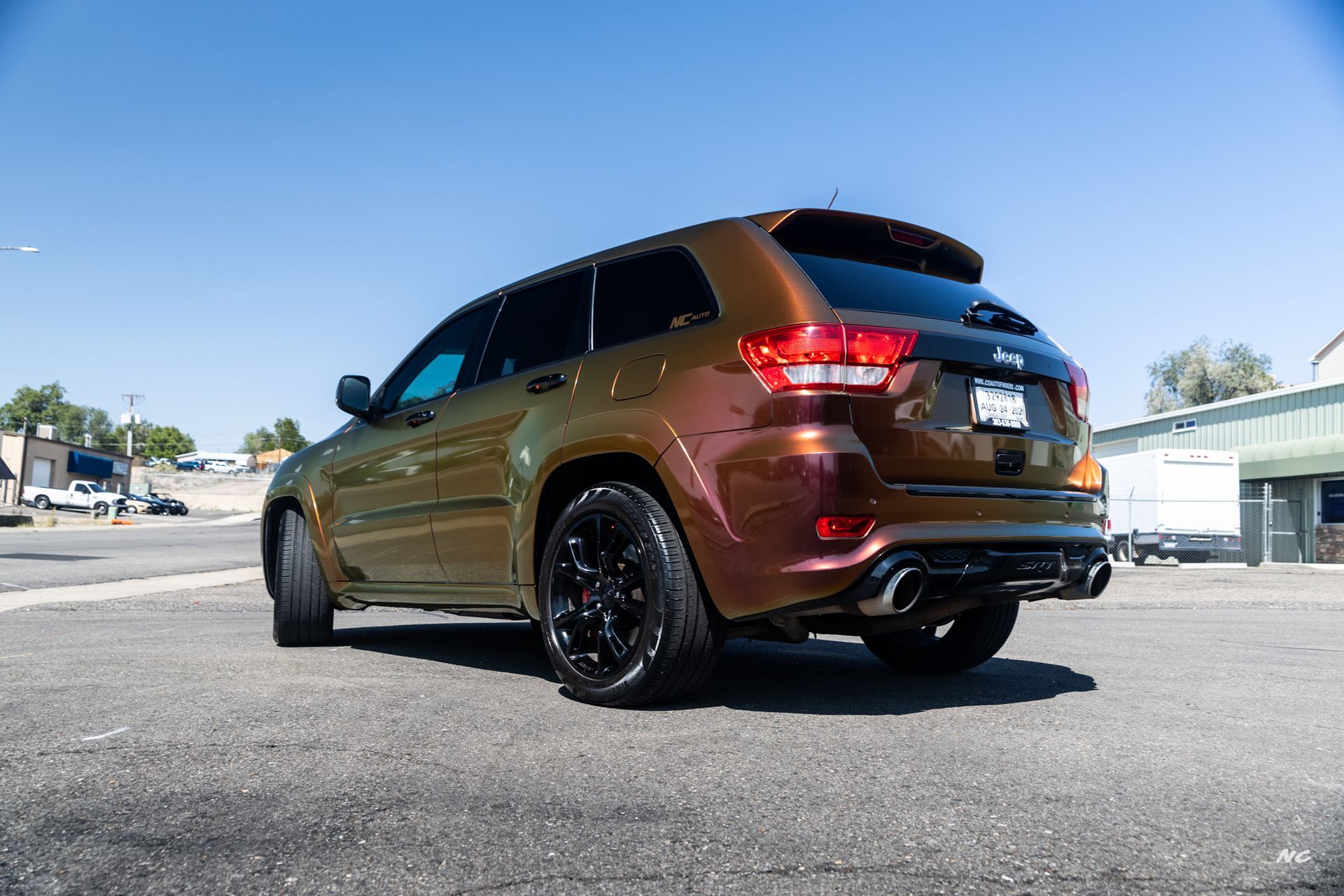Bronze-colored Jeep SUV parked on pavement on a sunny day. Black wheels, tinted windows.