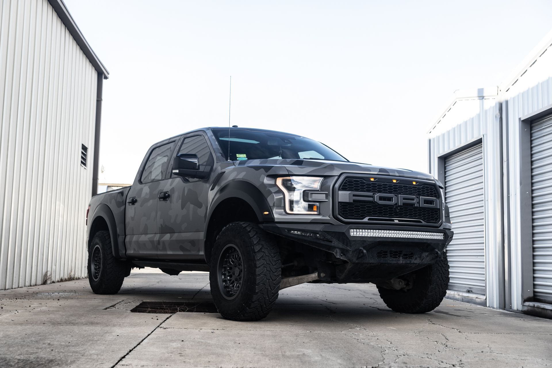Gray Ford Raptor truck parked outside a building.