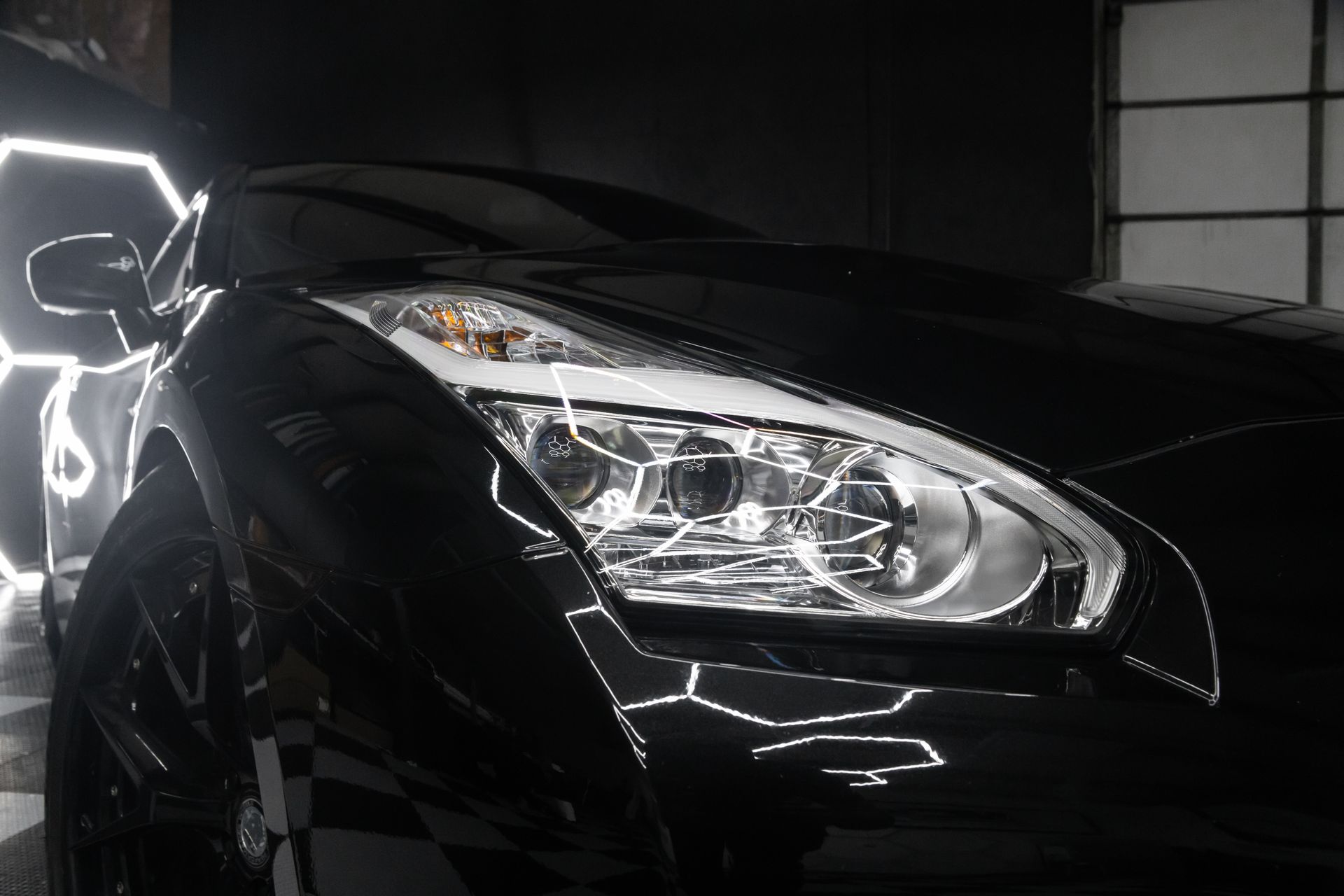 Black sports car with bright headlights; studio setting.