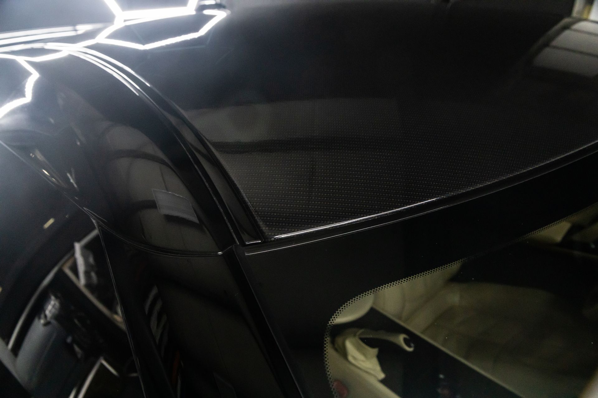 Black car roof with carbon fiber detailing, angled towards the windshield.