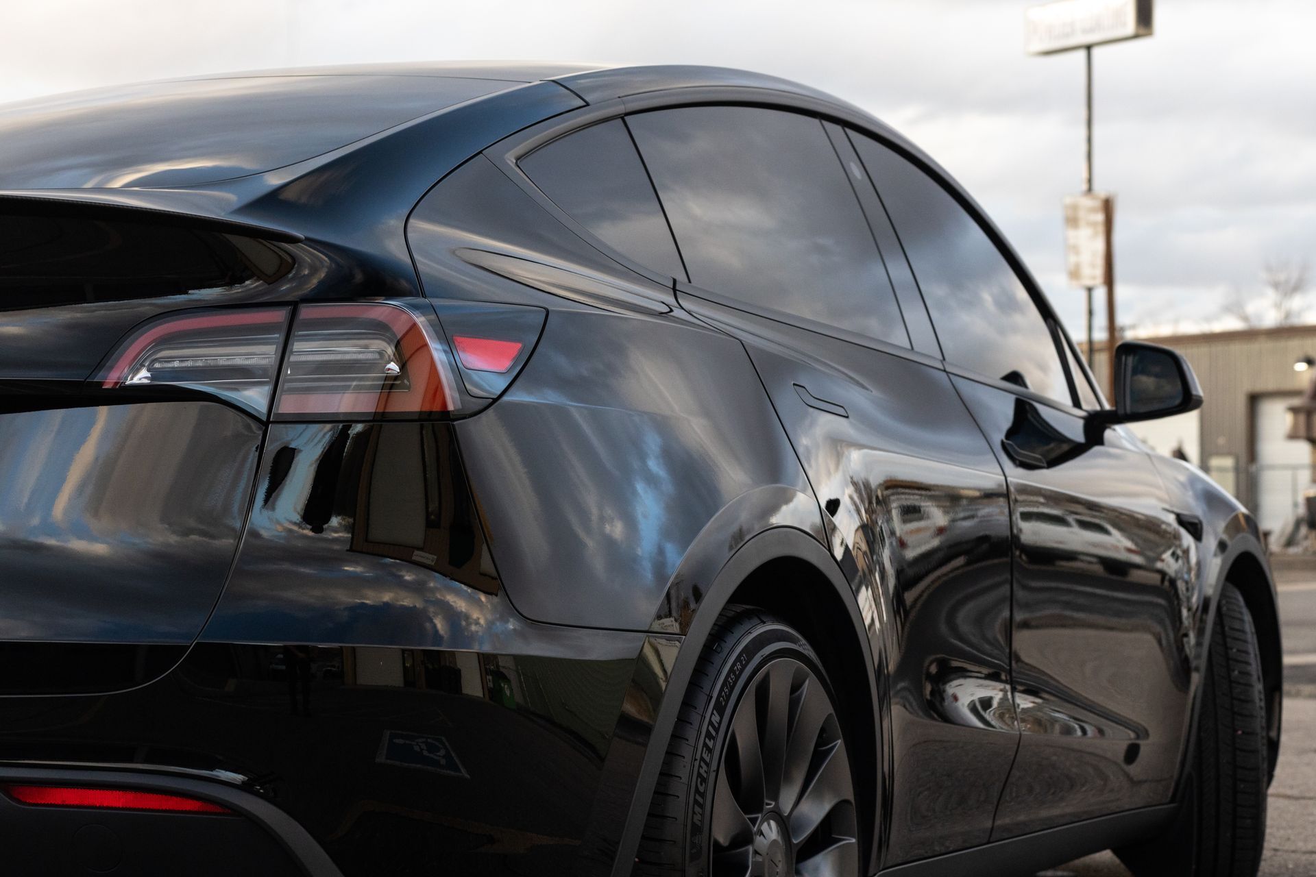 Black Tesla Model Y with tinted windows parked on a city street.