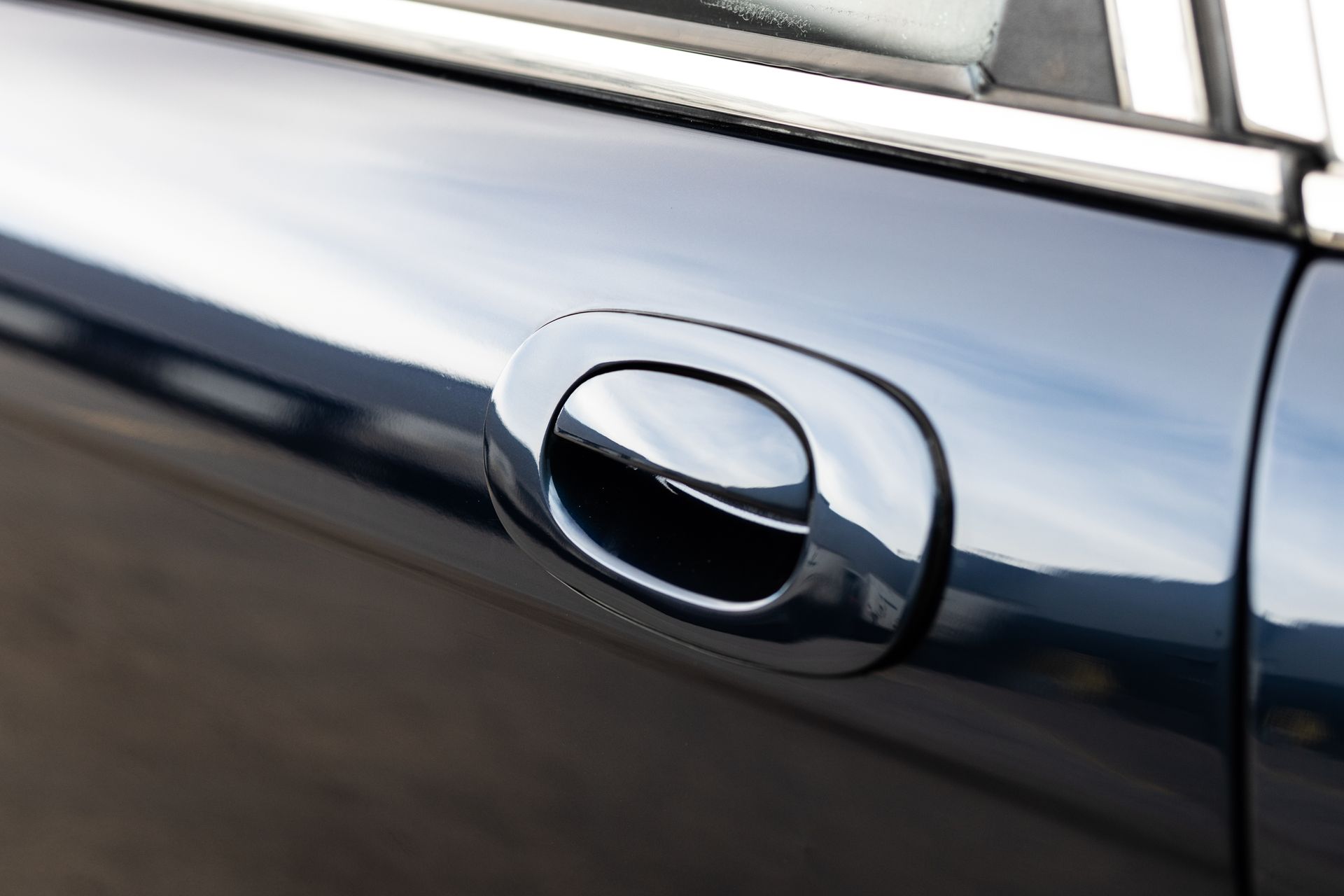 Chrome car door handle on a dark blue car.