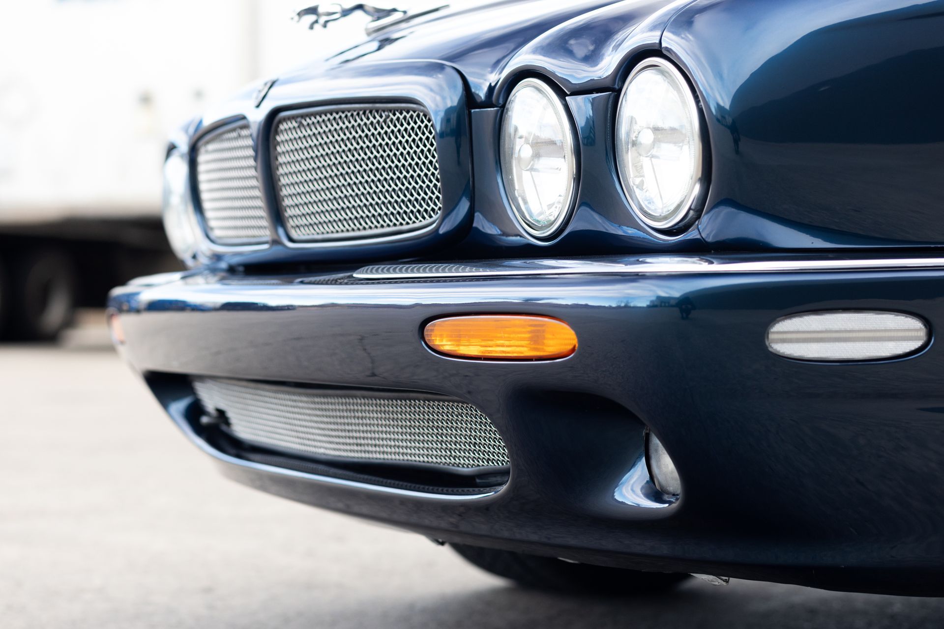 Blue Jaguar car front with round headlights, grill, and amber side marker.