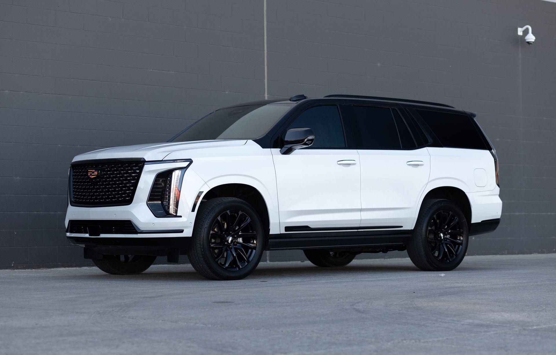 White SUV with black accents parked against a gray wall.