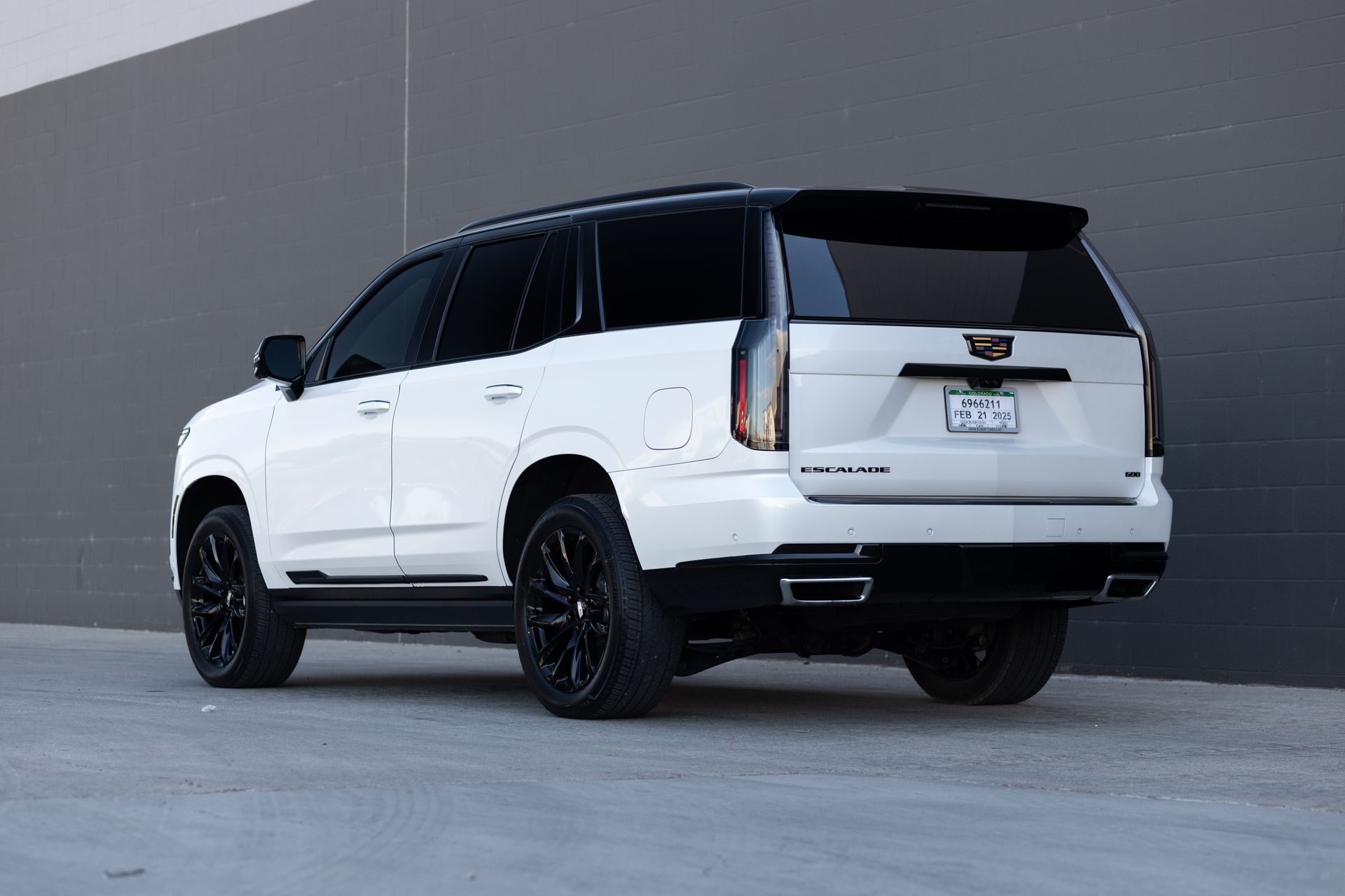 White Cadillac Escalade SUV with black accents, parked outside.
