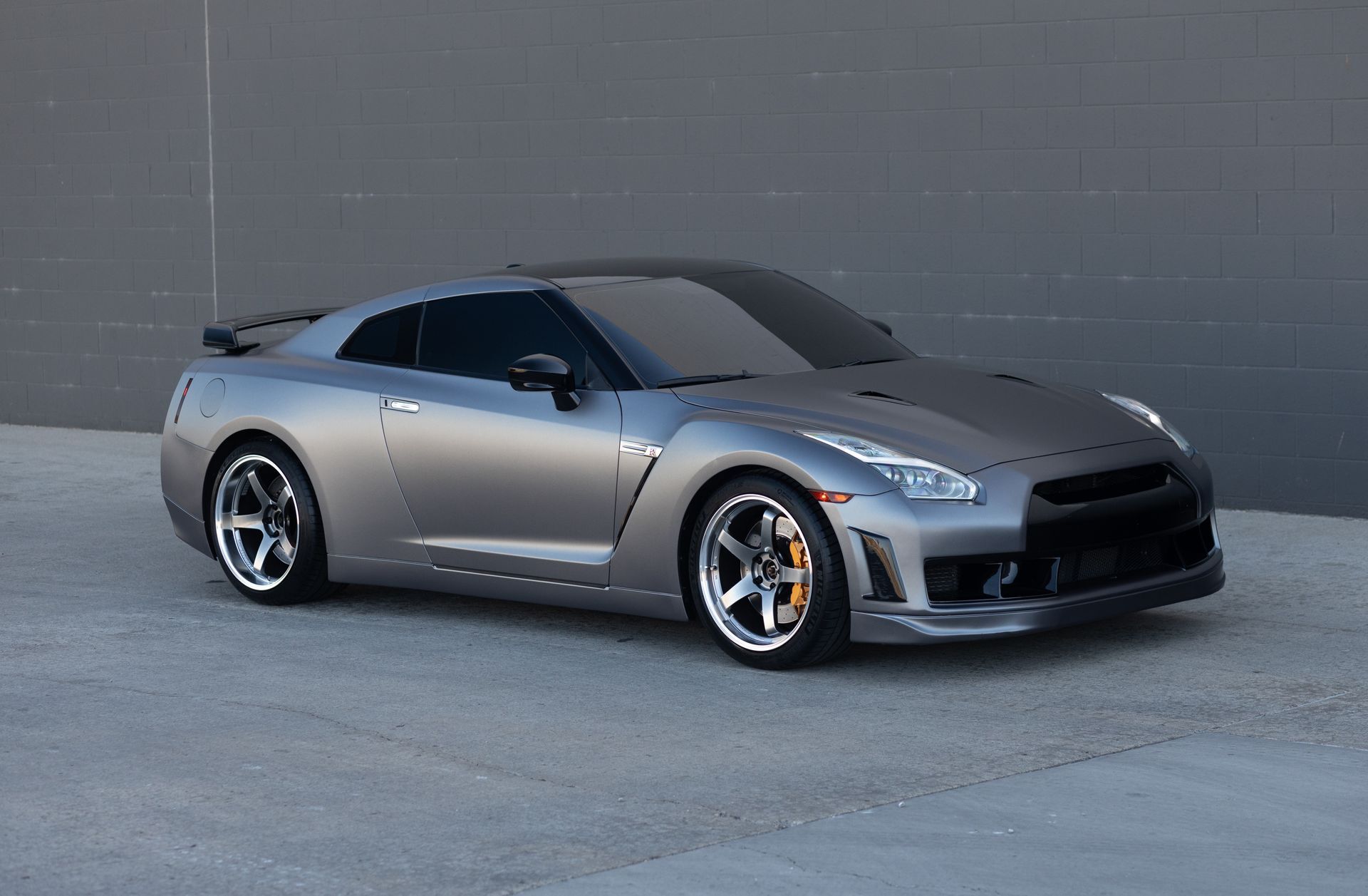 Gray Nissan GT-R sports car parked on concrete. Black accents, sporty wheels, and a dark roof.