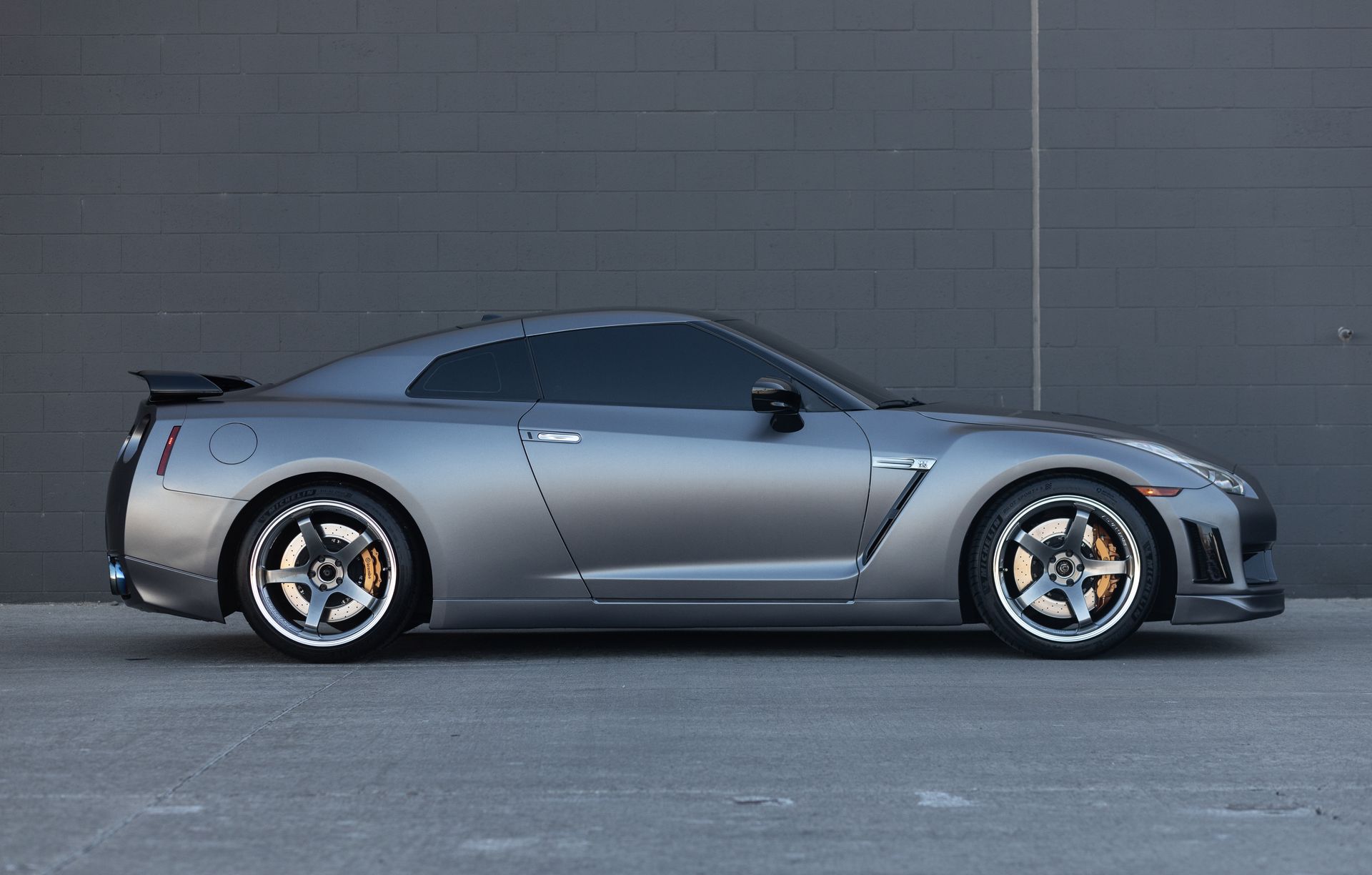 Gray Nissan GT-R sports car parked against a gray wall.