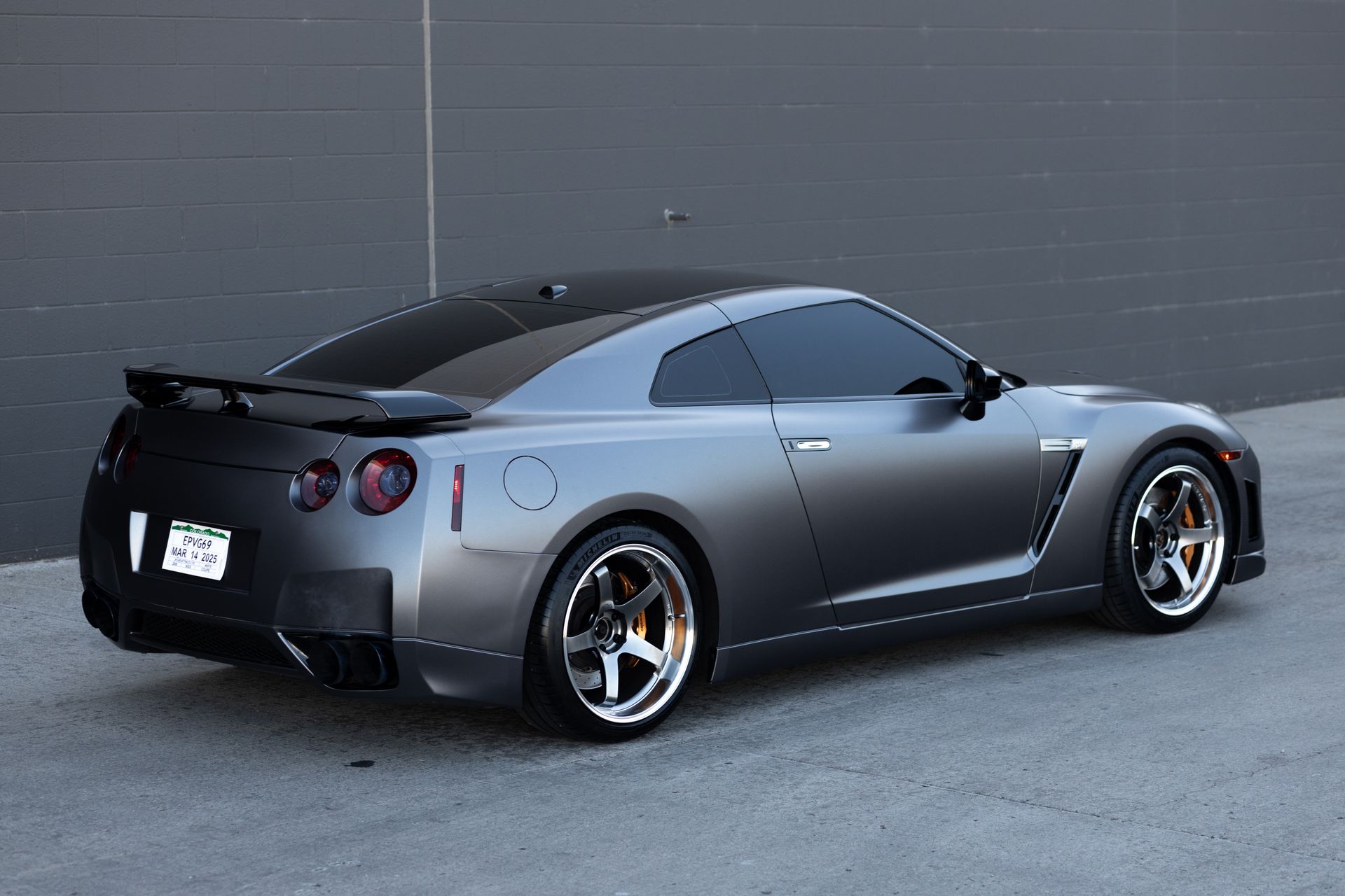 Gray Nissan GT-R sports car with tinted windows and black spoiler, parked on asphalt.