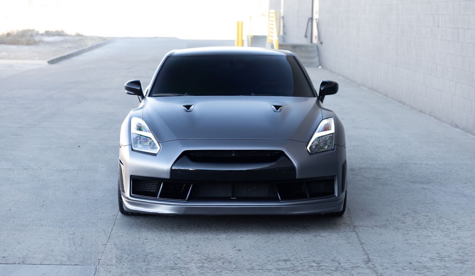 Gray Nissan GT-R sports car parked, facing forward on a concrete surface.