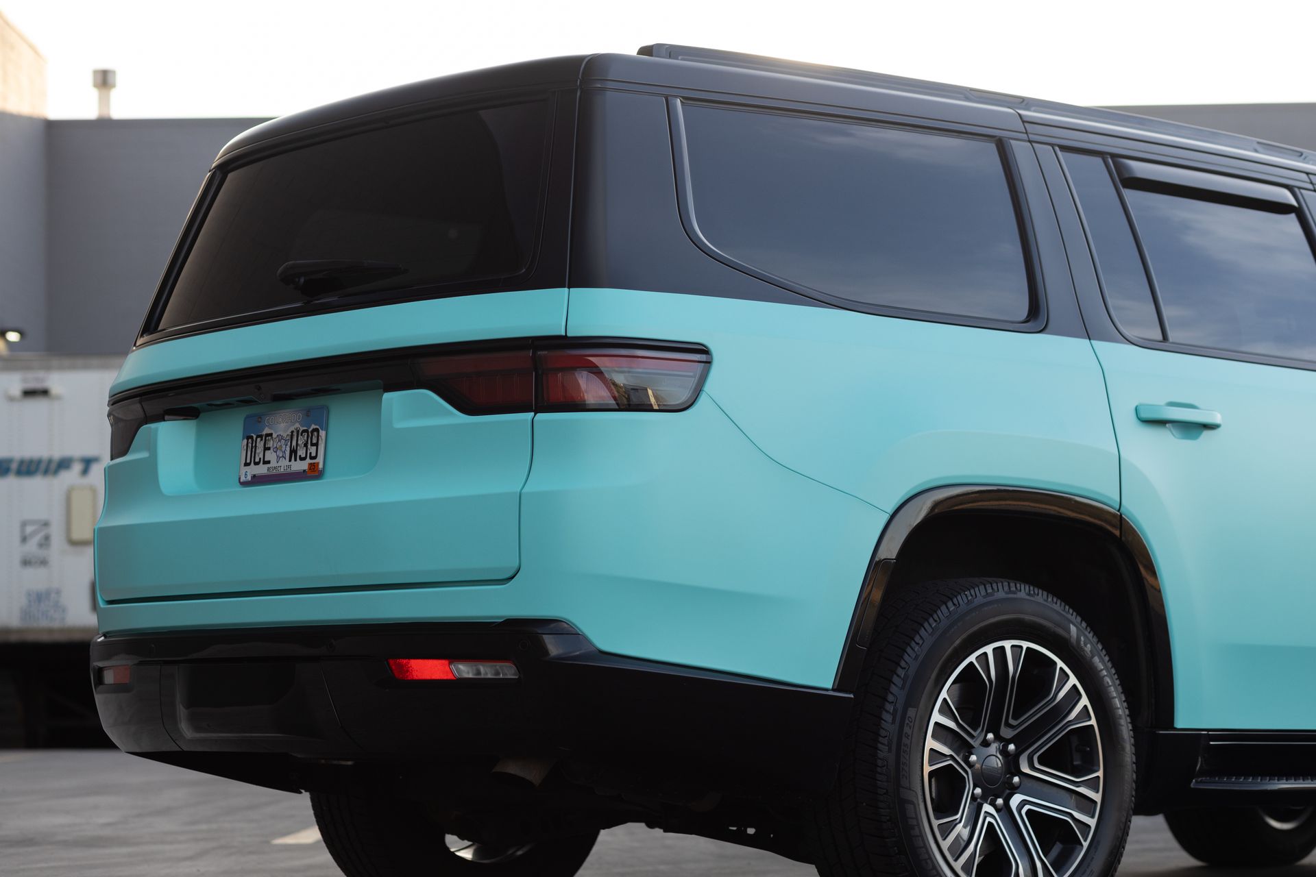 Aqua SUV with black roof and accents, parked outdoors, rear view.