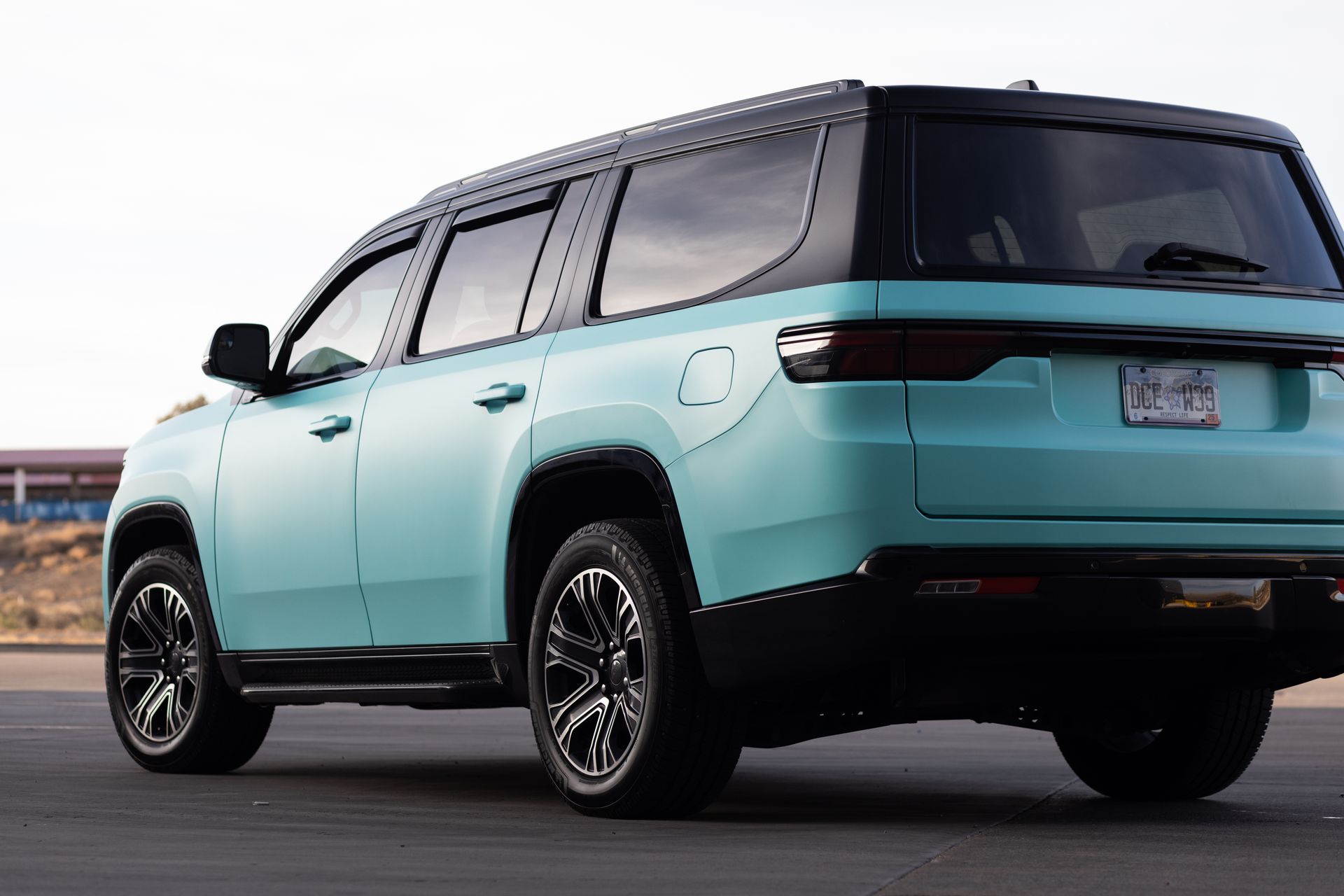 Turquoise SUV with black roof and wheels, parked outdoors.