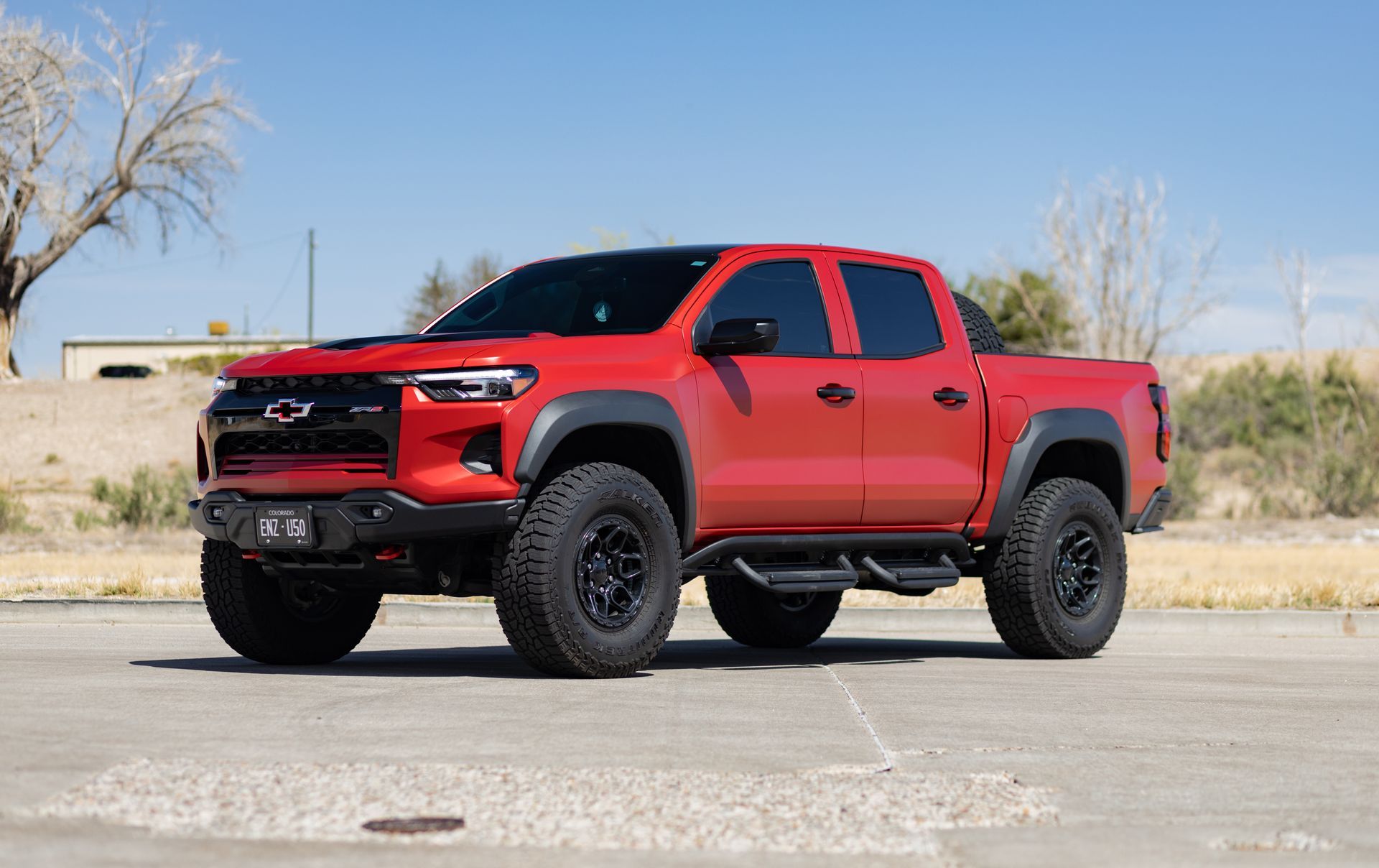 Red Chevrolet pickup truck with black wheels and fender flares, parked outdoors.