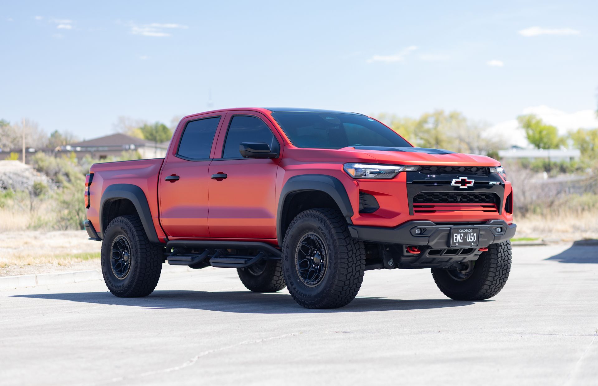 Red off-road pickup truck parked on a sunny day. Black wheels, tinted windows.
