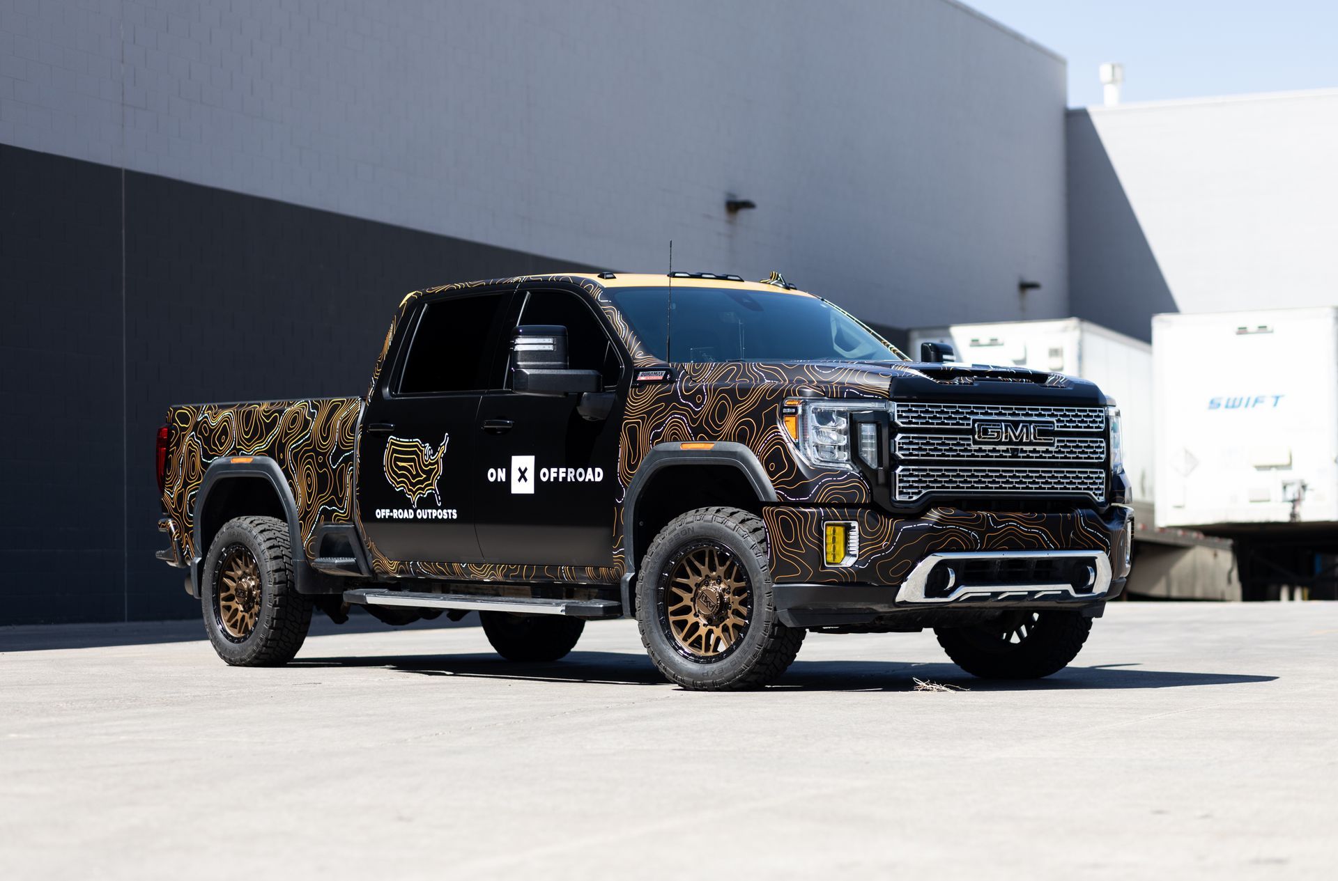 Black pickup truck with gold accents, parked outside a building.