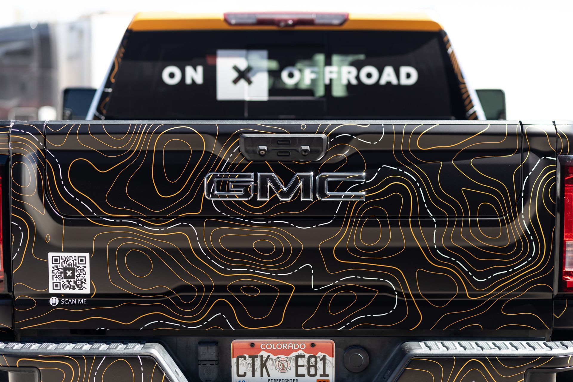 Black GMC truck with topographic-style graphic, 