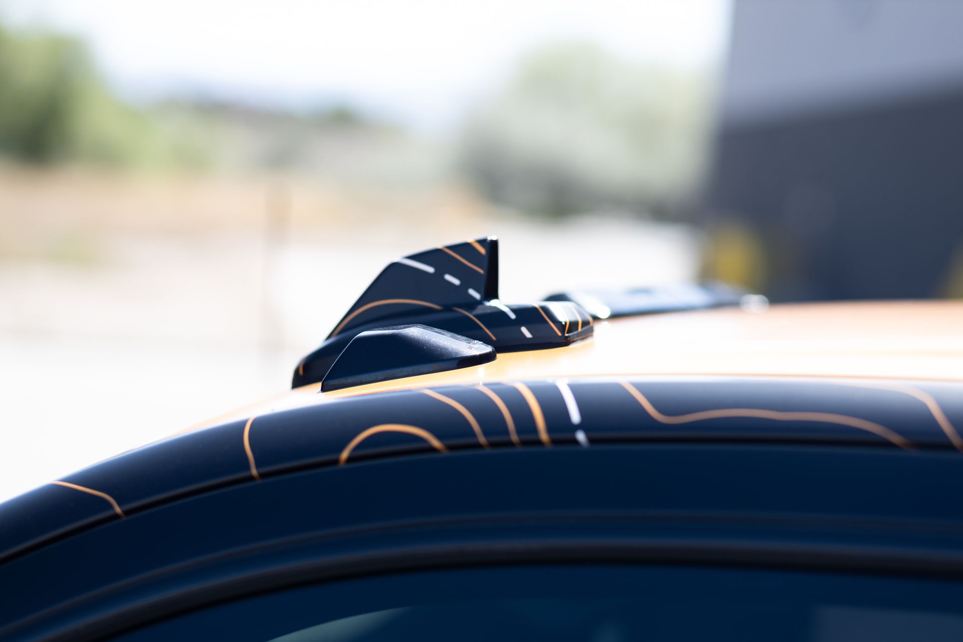 Black car roof with GPS-themed graphic and shark fin antenna, set outdoors.