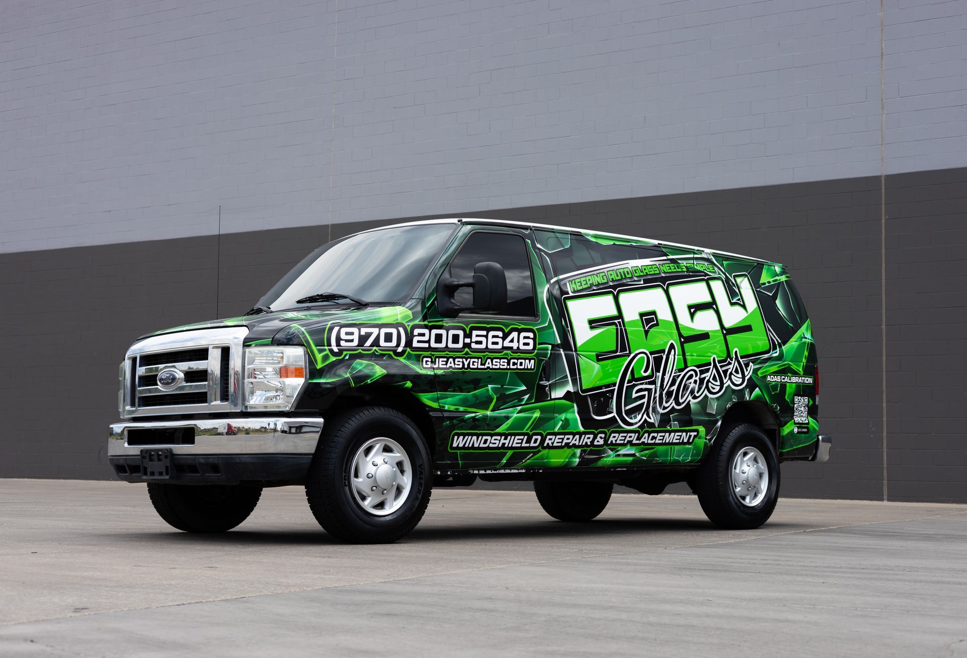 Green and black branded service van with business logo and phone number.