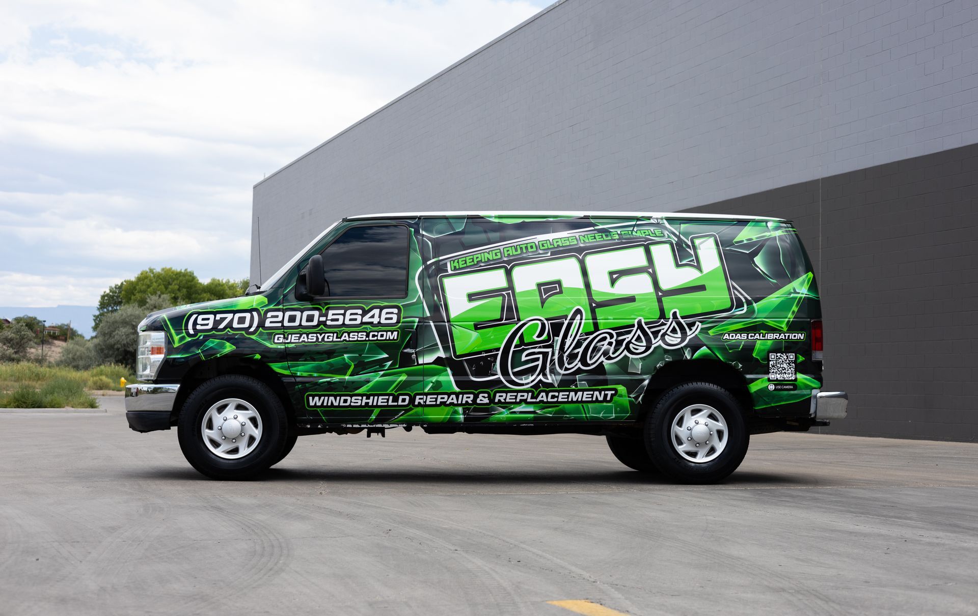 Green and black Easy Glass van with business details on side, parked outside.
