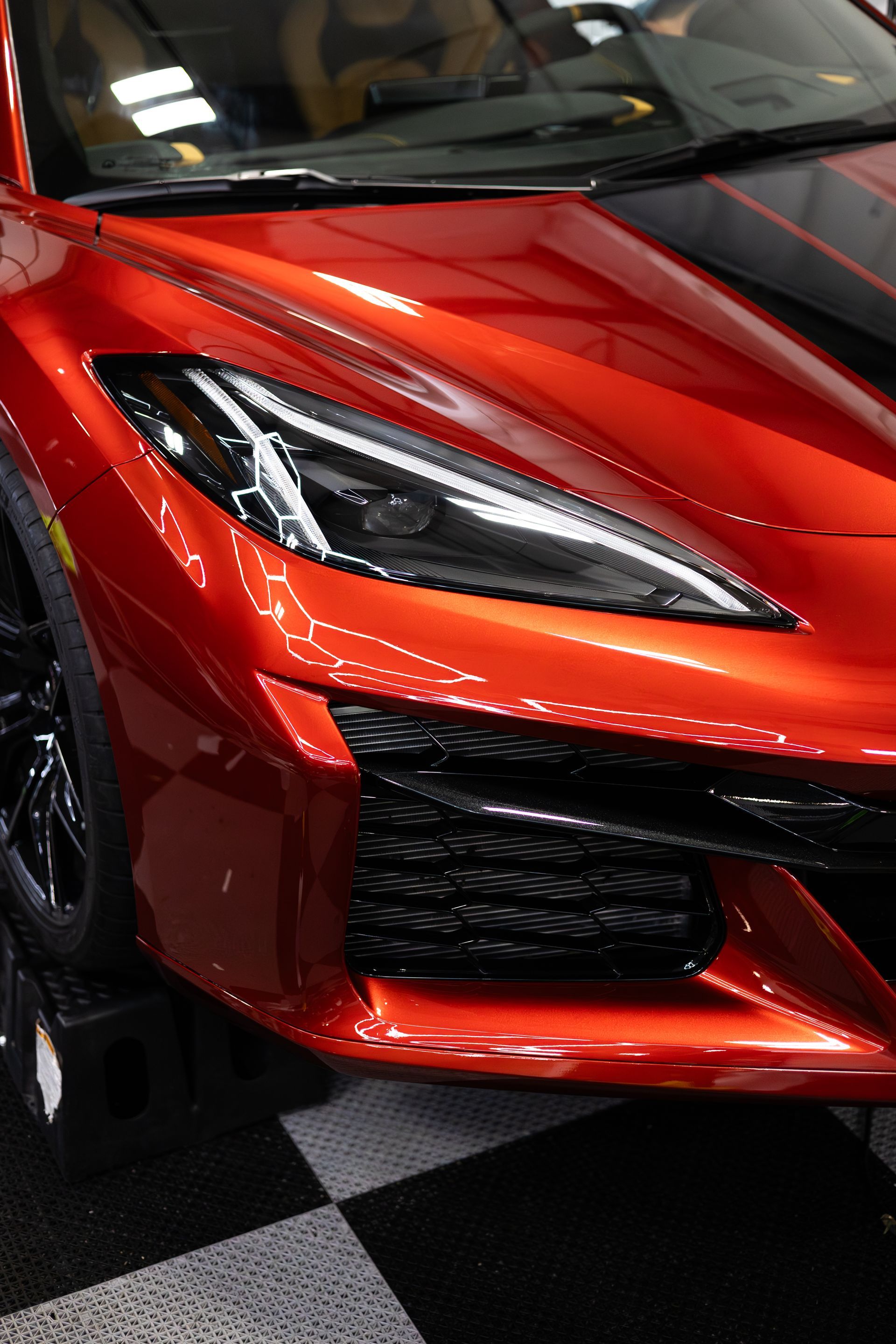 Red sports car, close-up of front end, black grill and headlight, glossy finish.