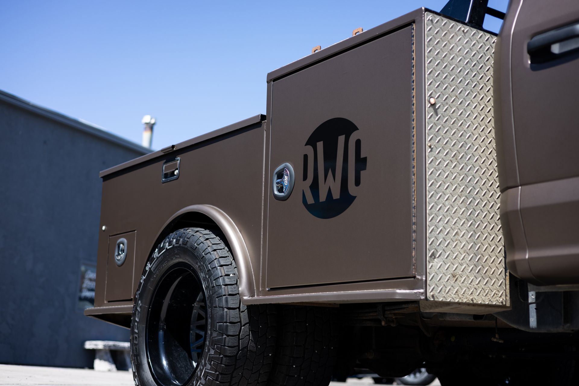 Brown truck bed with toolboxes and black wheels. 