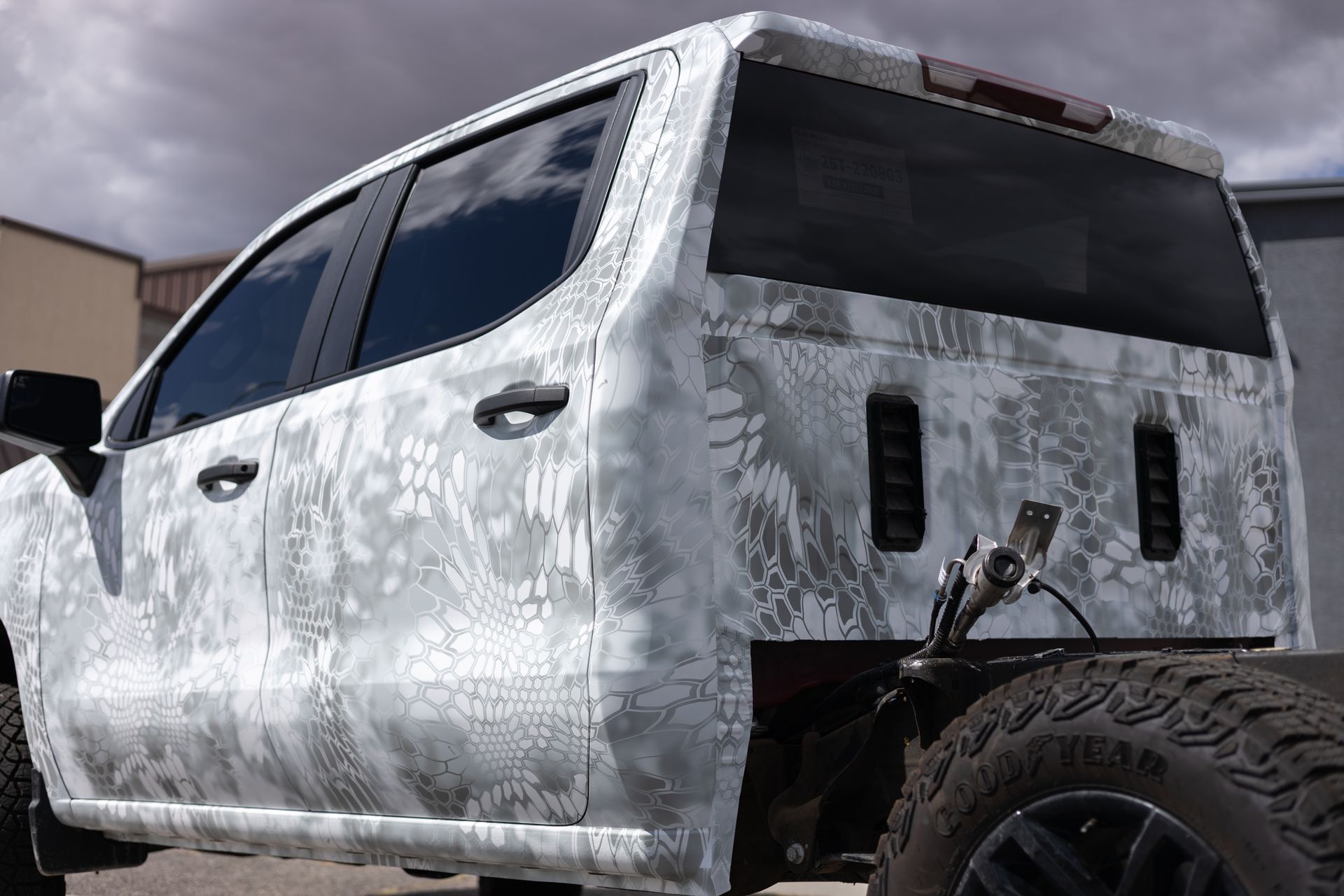 White camouflage pickup truck's cab and chassis, parked outside.