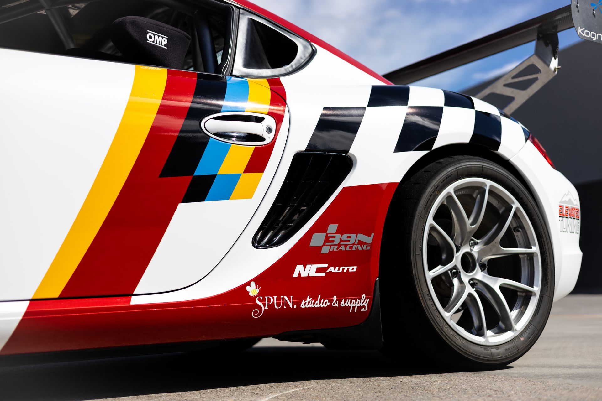 White race car with red and yellow stripes, black and white checkered accents, and sponsor logos on the side.