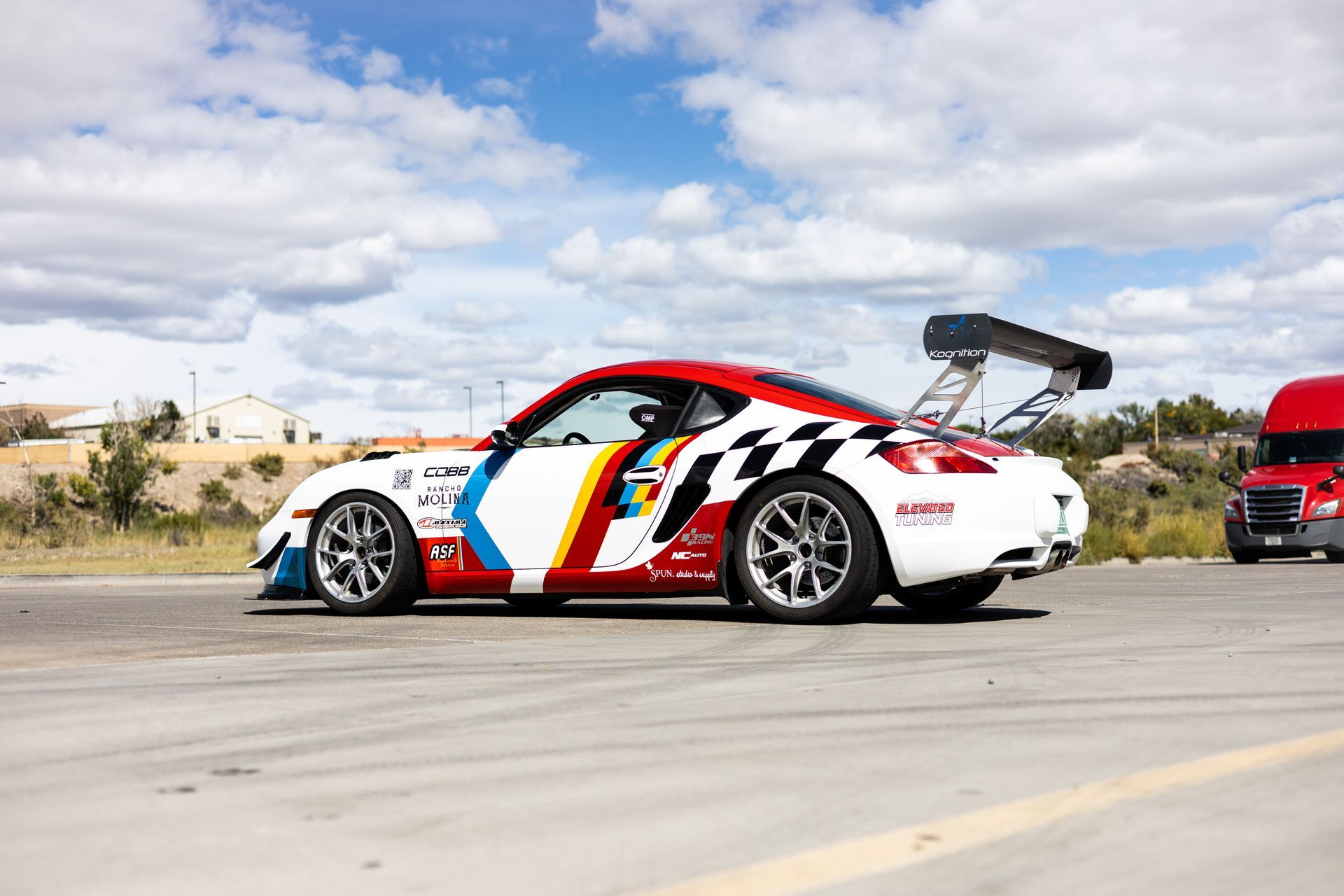 White, red, and blue race car with large spoiler on track.