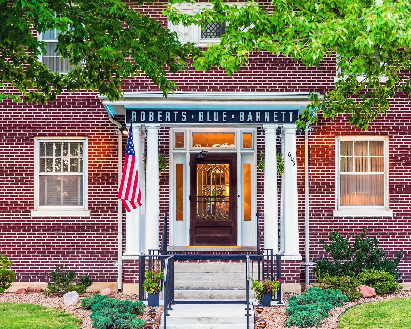 The front door of a house with a porch and plants in front of it.