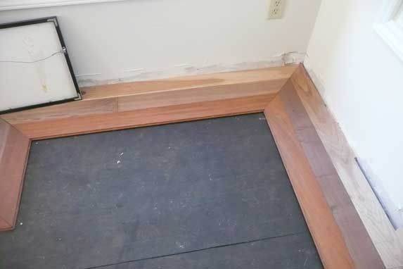 Wooden door frame partially installed on a dark floor against white walls.