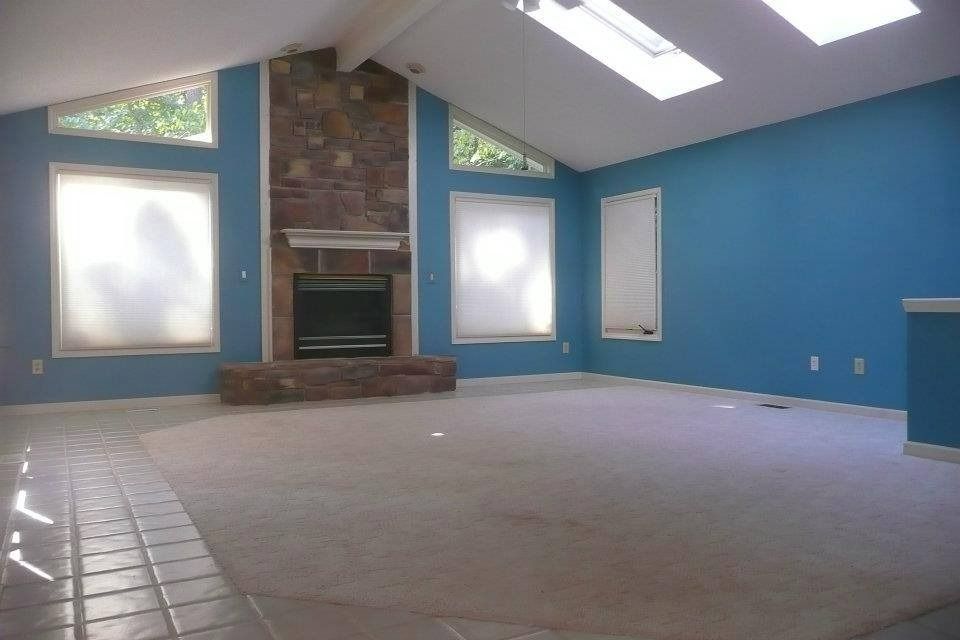 Spacious living room with blue walls, a fireplace, and skylights.