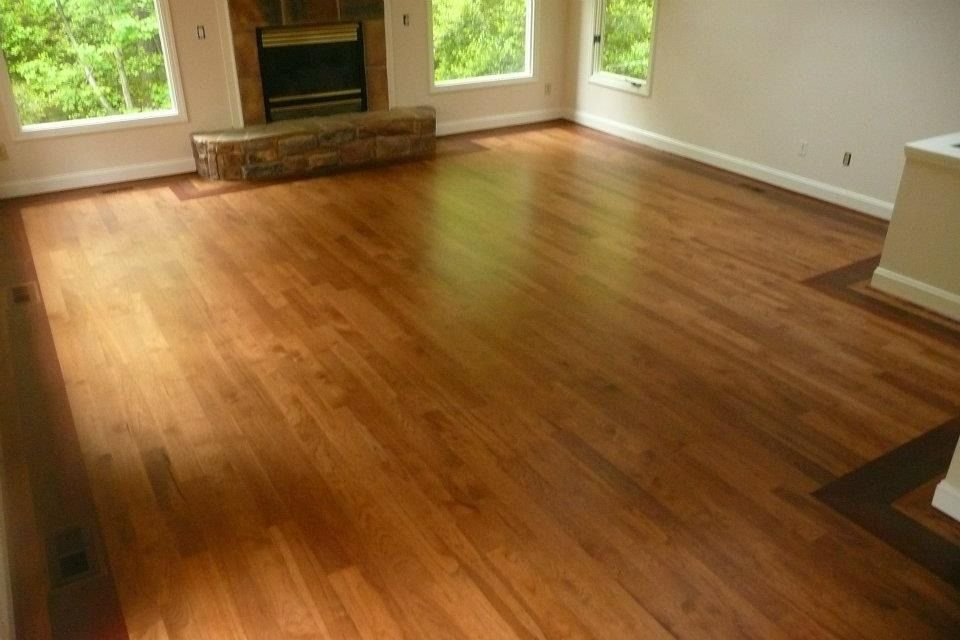 Hardwood floor in a living room with a fireplace and windows.