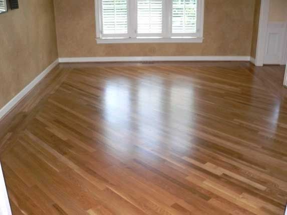 Hardwood floor in room with window, light reflecting off the glossy wood.