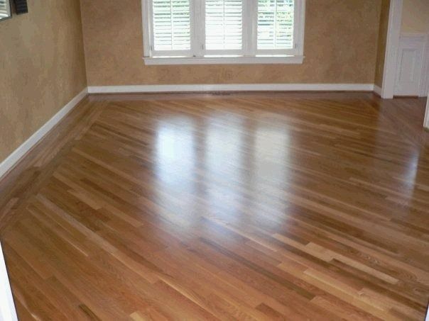 Wooden floor with diagonal pattern, reflecting light from a window, in a room.