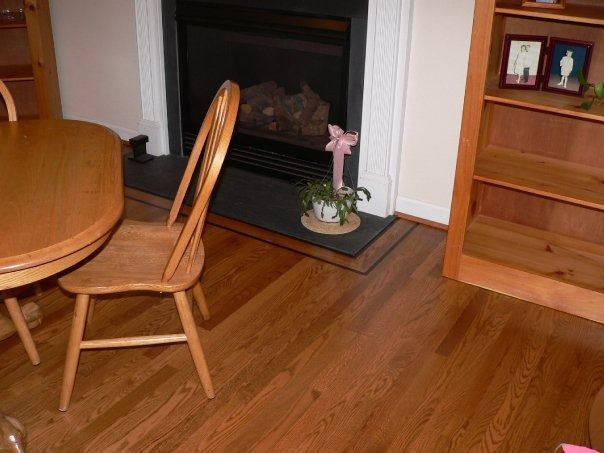 Wooden chair near a fireplace with a small plant and a bookshelf in a room with hardwood floors.